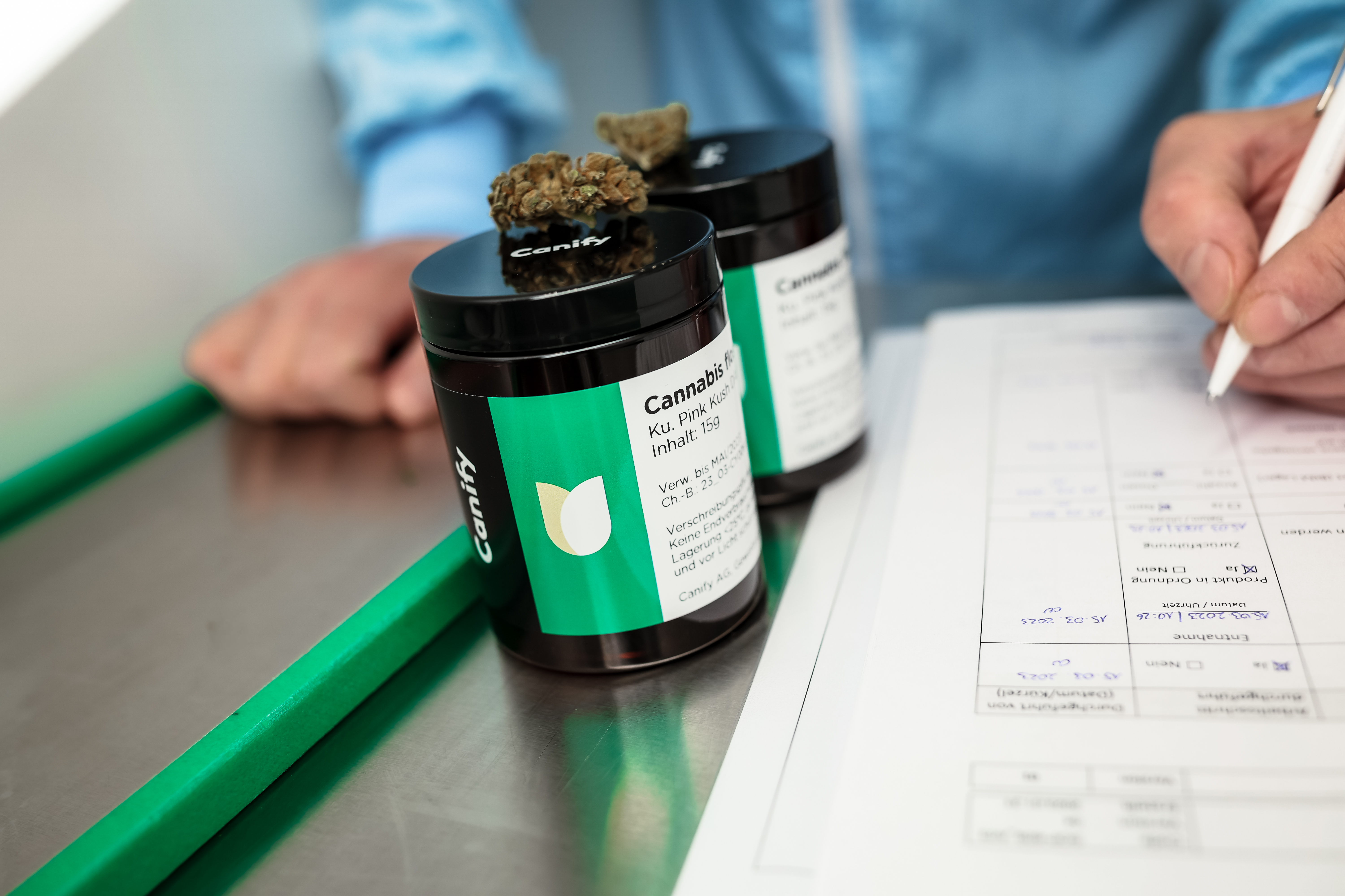 Canify-Produktdosen auf einem GMP-Prüftisch: Ein Mitarbeiter dokumentiert die Chargenprüfung auf einem Kontrollformular